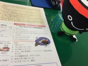 A small toy of local mascot “Omocchi” looks on with interest at the latest edition of ILC News, especially the bit about his new brother “ILC Sobacchi.”