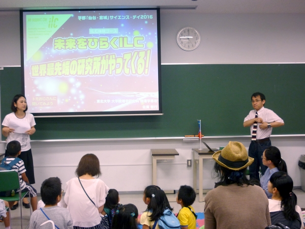 Dr. Tomoyuki Sanuki (right) gives a presentation on the ILC. You may know Dr. Sanuki from the ILC Scouts videos, where he teaches a young audience about physics.